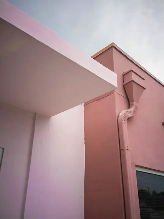 Esquina de un edificio rosa bajo un cielo nublado
