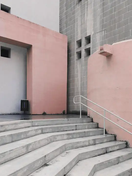 Escalera de piedra que sube hacia un edificio rosa