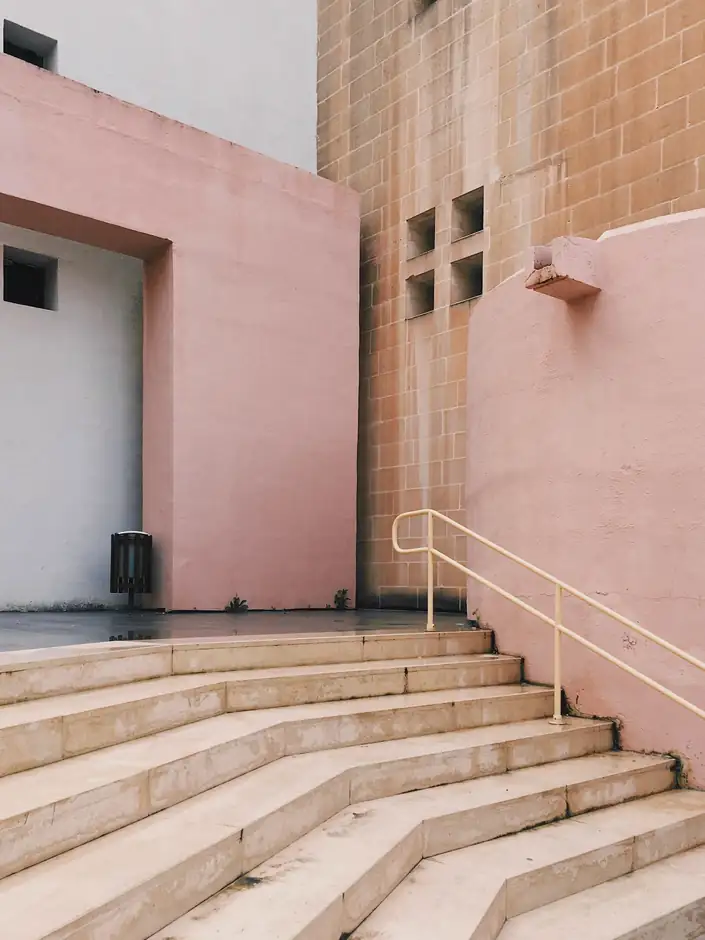 Escalera de piedra que sube hacia un edificio rosa