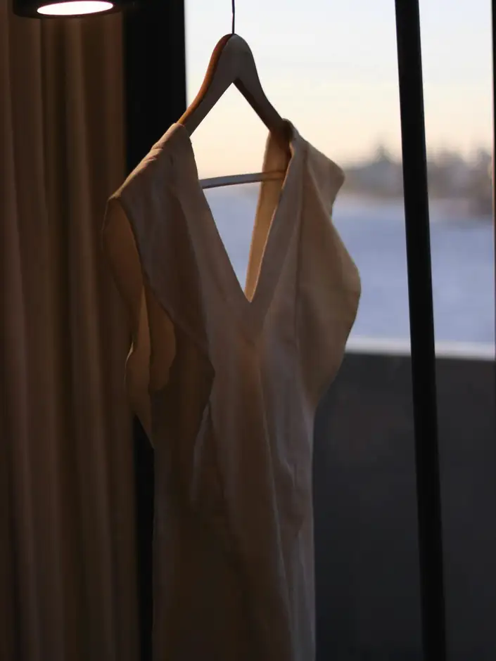 Vestido colgado de una percha frente a una ventana al atardecer