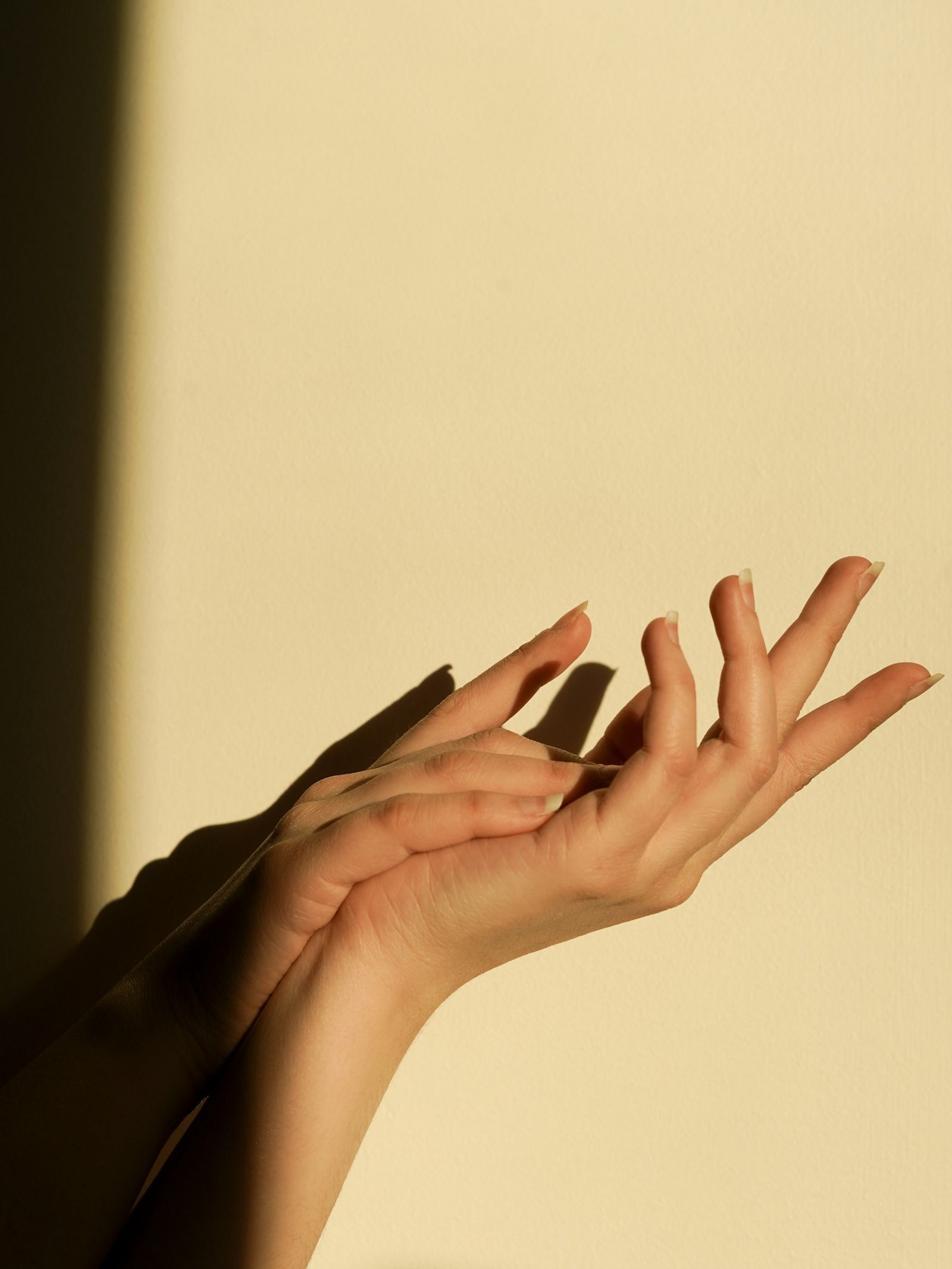 Manos abiertas con luz de tarde sobre la pared
