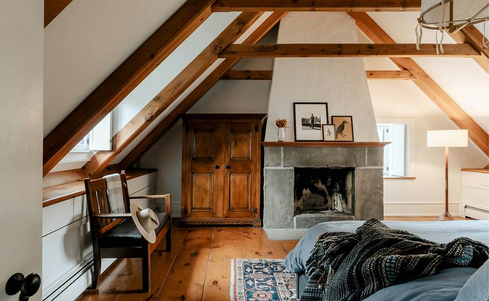 Buhardilla de madera con vigas vistas y una chimenea de piedra
