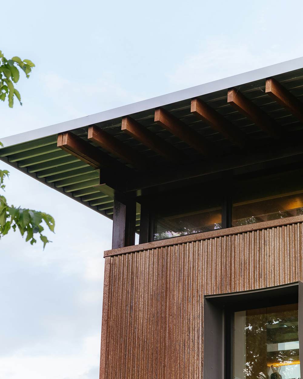 Volumen de madera con alero de vigas vistas y ventana al jardín