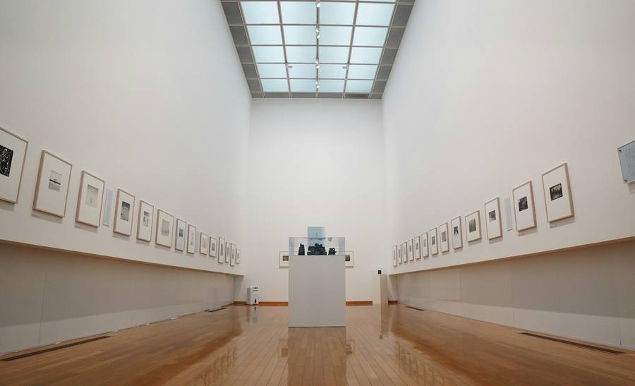 Sala de exposiciones con marcos en las paredes y piso de madera