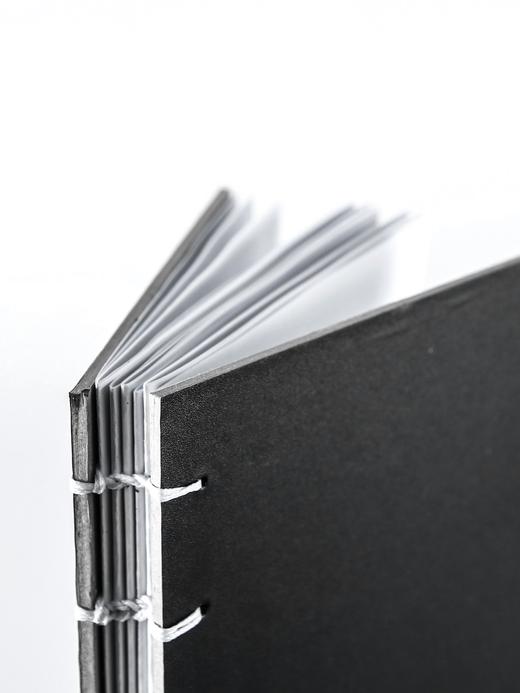 Cuaderno de tapa negra con la costura a la vista