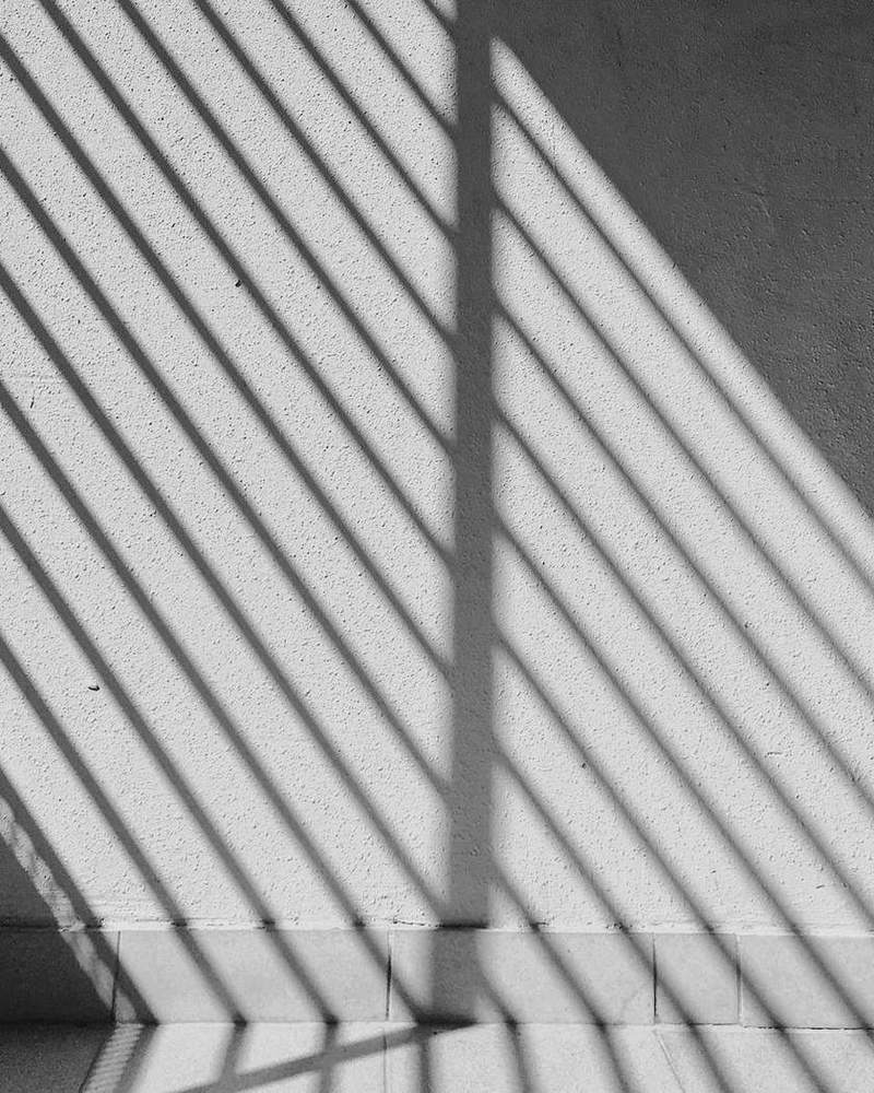 Franjas de sombra proyectadas sobre una pared lisa, en blanco y negro