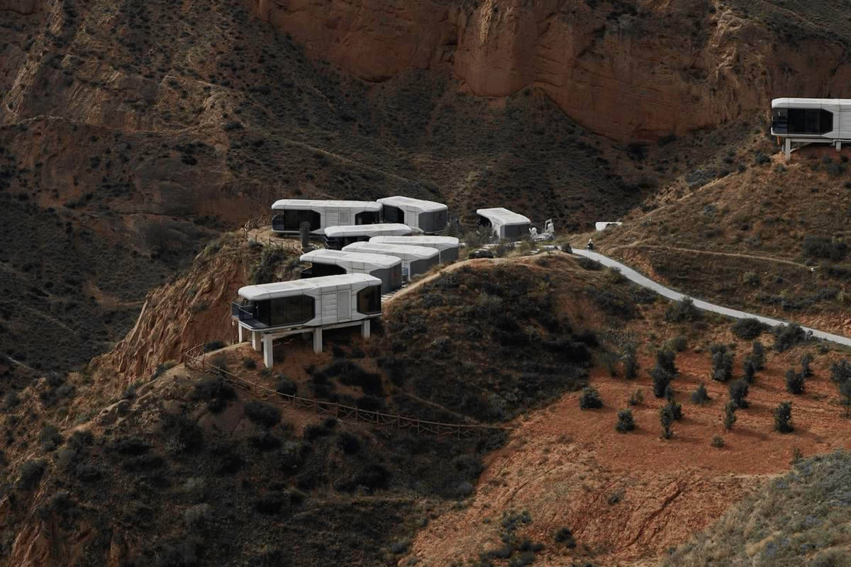 Cabañas blancas dispersas en una ladera de montañas rojizas