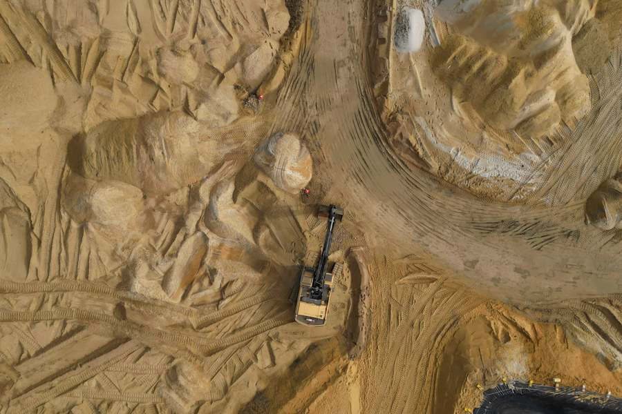 Vista aérea de una excavadora moviendo tierra arenosa en un terreno