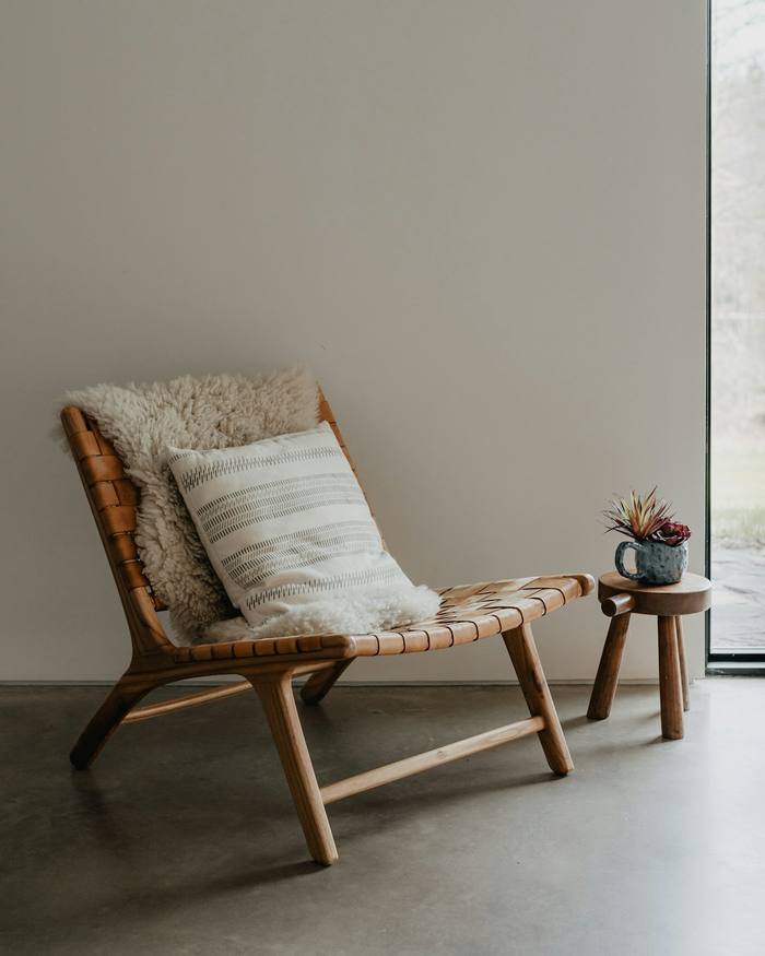 Sillón de lectura de madera y cuero trenzado, con una manta de lana