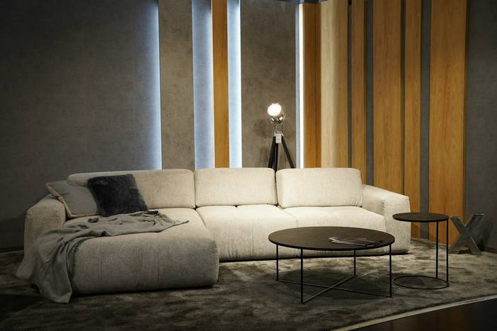 Sofá modular crema con una mesa baja redonda en una sala sobria