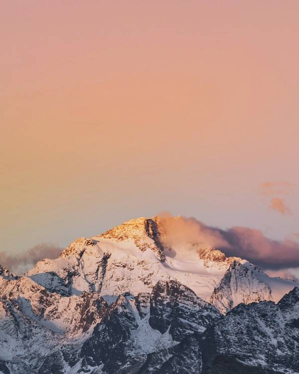 Cumbre nevada teñida de rosa y naranja al amanecer