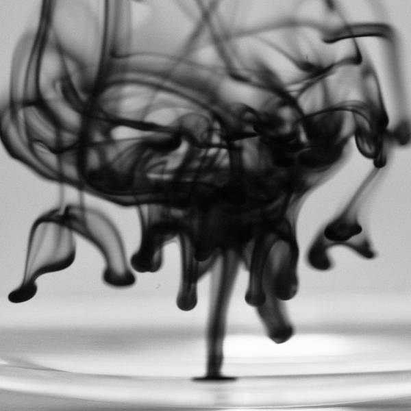 Filamentos de tinta negra que caen dentro de un vaso