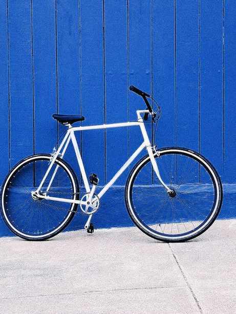 Bicicleta blanca contra una pared de madera azul