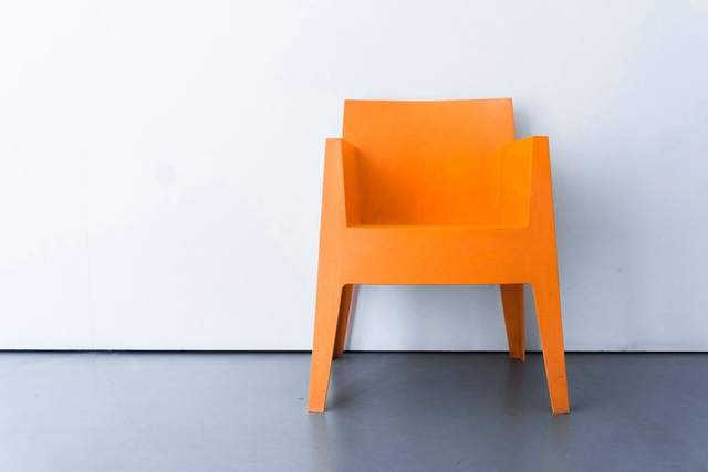 Silla de plástico naranja contra una pared blanca