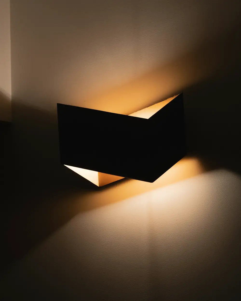 Aplique angular de metal que lanza luz cálida hacia arriba y hacia abajo