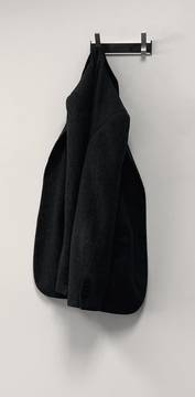 Una chaqueta negra colgada de un gancho en una pared blanca