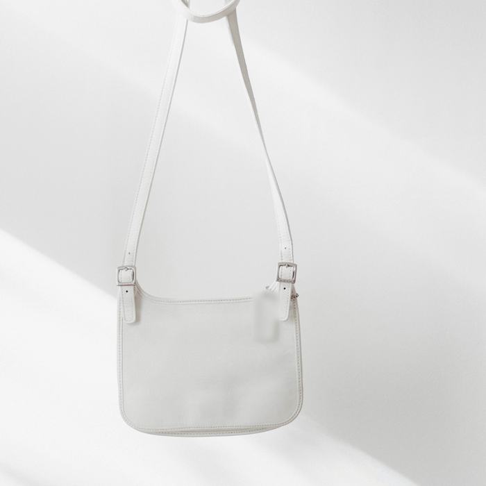 Bolso blanco hueso colgado de una barra por su correa larga