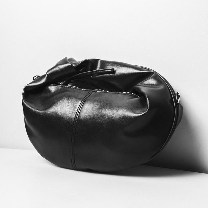 Bolso negro de cuero con forma de saco, sobre un fondo blanco