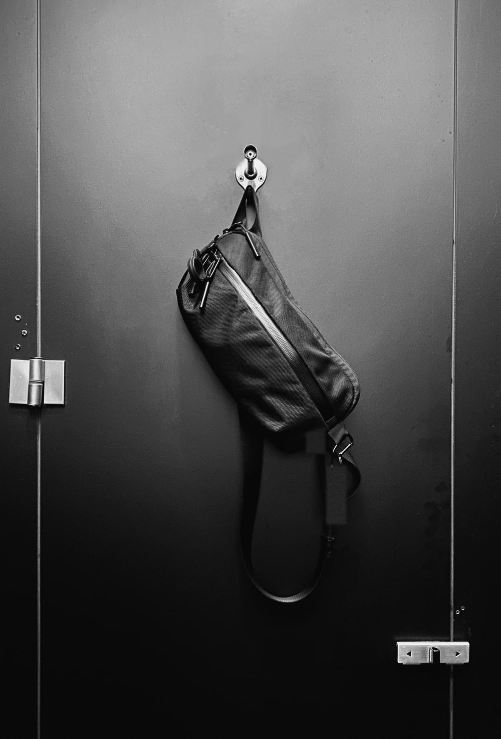 Bolso negro colgado de un gancho en una puerta oscura