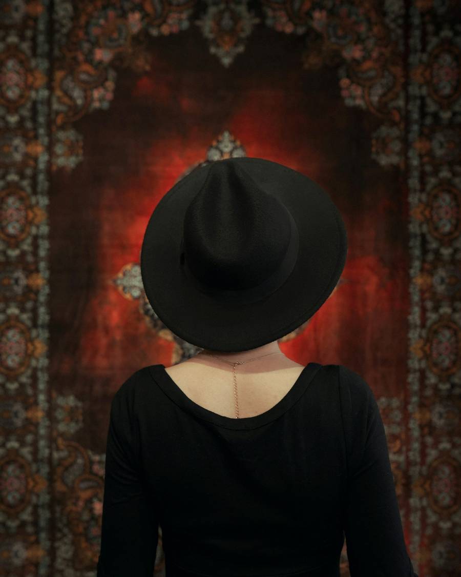 Persona de espaldas con sombrero negro frente a una alfombra roja