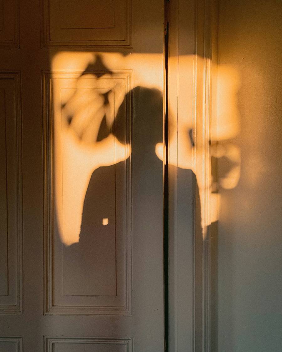 Silueta dorada de una persona contra una pared iluminada