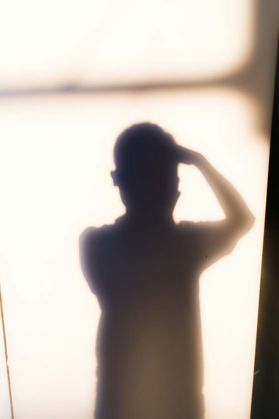Silueta de una persona contra una pared blanca, sin rostro visible