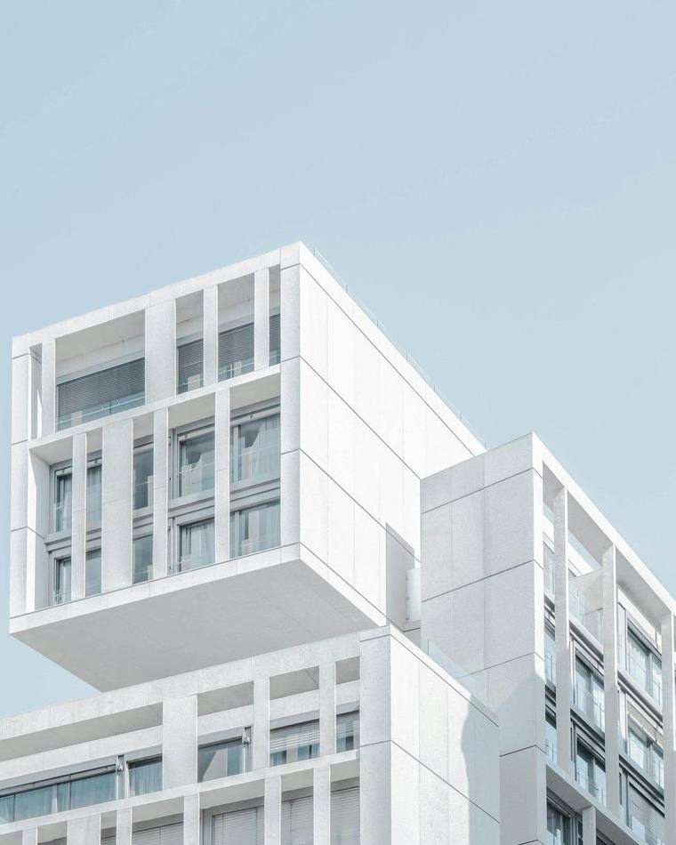 Edificio blanco de volúmenes superpuestos contra un cielo azul pálido