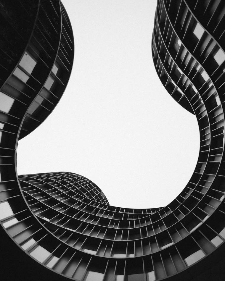 Fachada curva de un edificio vista desde abajo, en blanco y negro