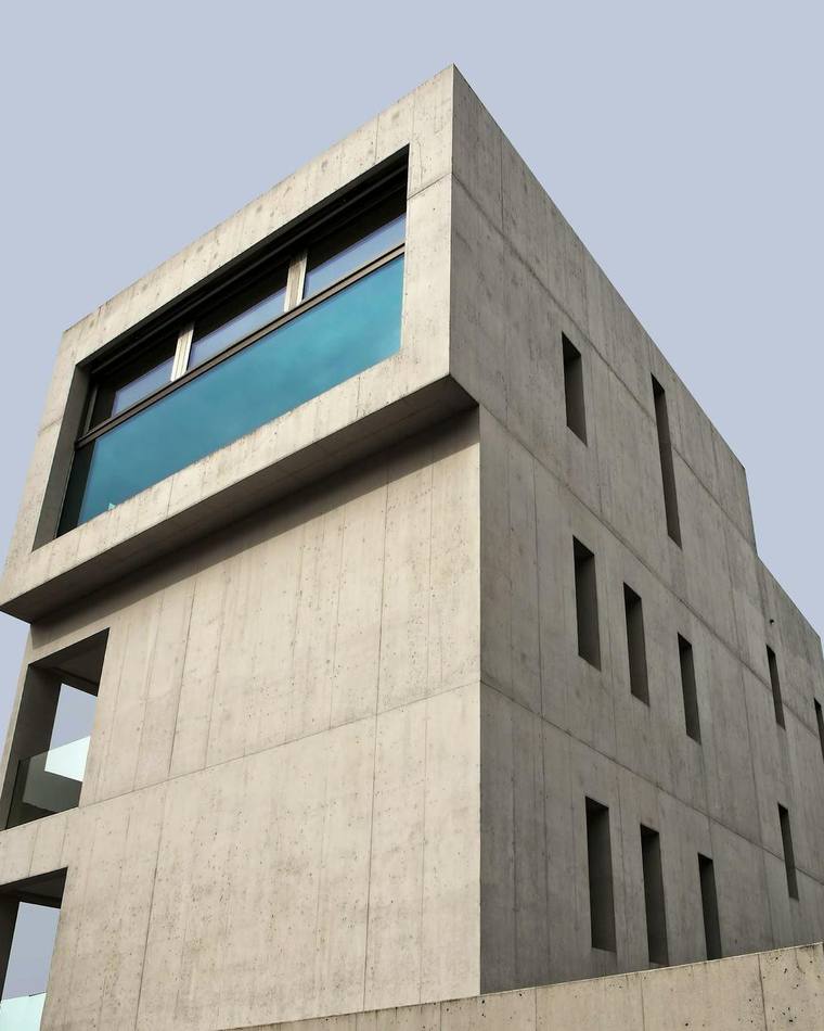 Volumen de hormigón con una ventana alargada que refleja el cielo
