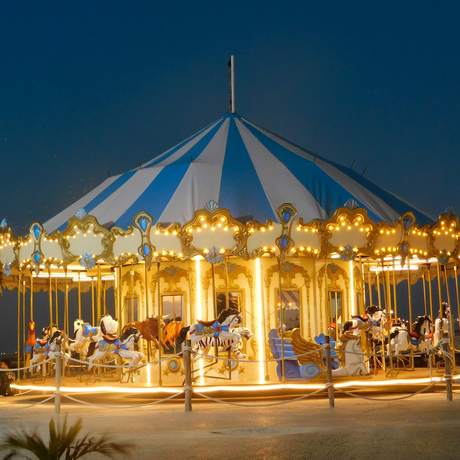 Carrusel con toldo azul y blanco iluminado al anochecer