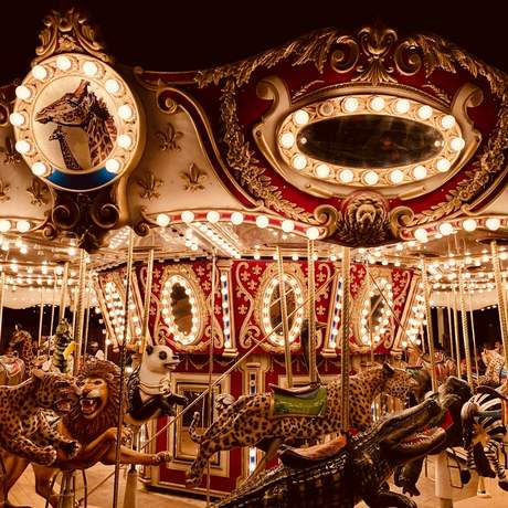 Detalle de un carrusel antiguo con bombillas y caballos de madera