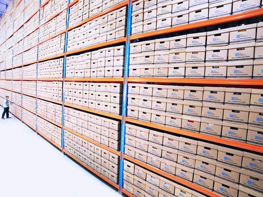 Un largo pasillo de estantes con cajas de archivo