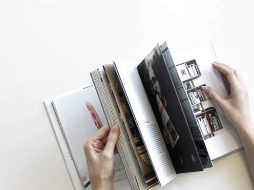 Manos hojeando un libro de fotografías sobre una mesa blanca