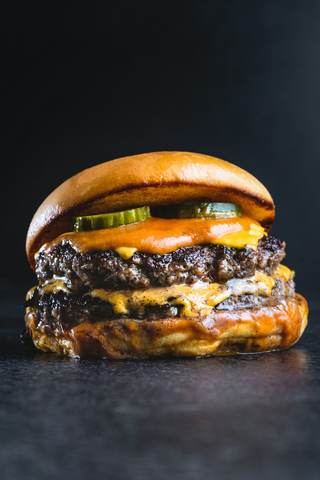 Hamburguesa doble con queso sobre fondo oscuro
