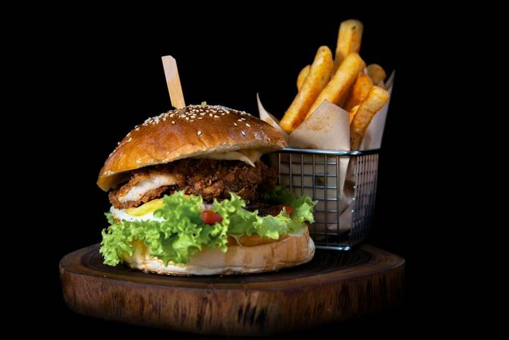 Hamburguesa con papas fritas sobre fondo negro