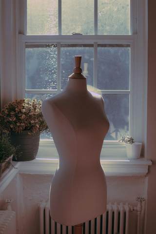 Maniquí de costura junto a una ventana