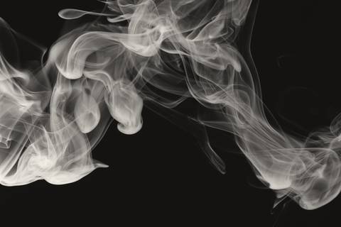 Hebras de humo blanco que se enroscan sobre fondo negro