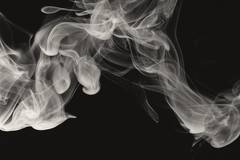 Hebras de humo blanco que se enroscan sobre fondo negro