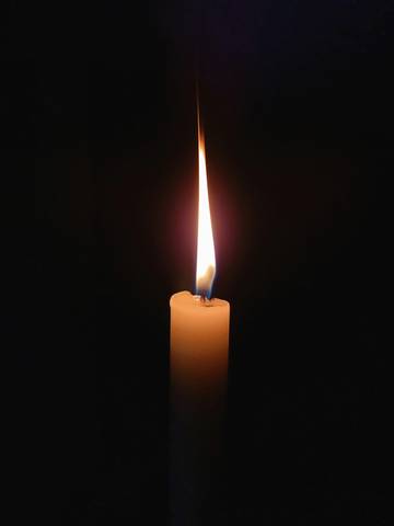 Llama de una vela encendida en la oscuridad