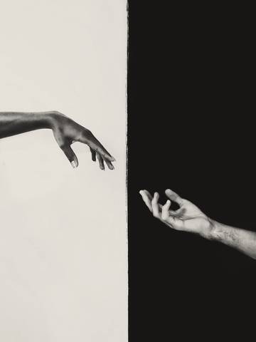 Dos manos que se acercan a través de un fondo dividido en blanco y negro