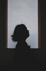 Silueta de perfil junto a una ventana con el cielo claro