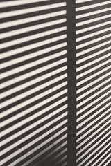 Franjas de luz y sombra de una persiana sobre un muro