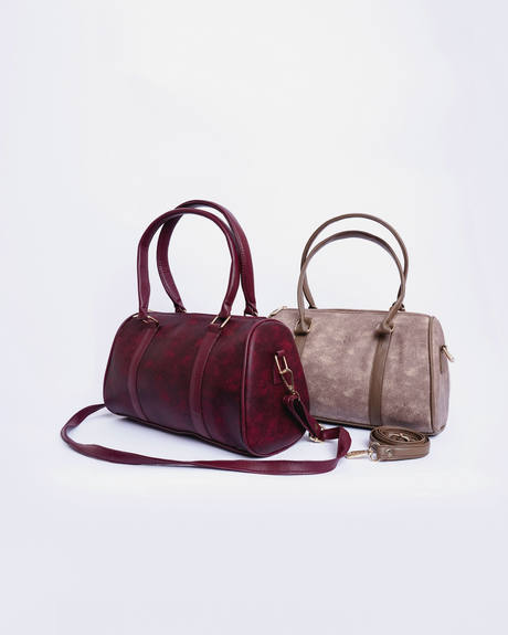 Dos bolsos cilíndricos, uno granate y otro color visón, sobre fondo claro