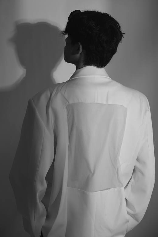 Espalda de una chaqueta blanca con un panel de tela transparente, en blanco y negro