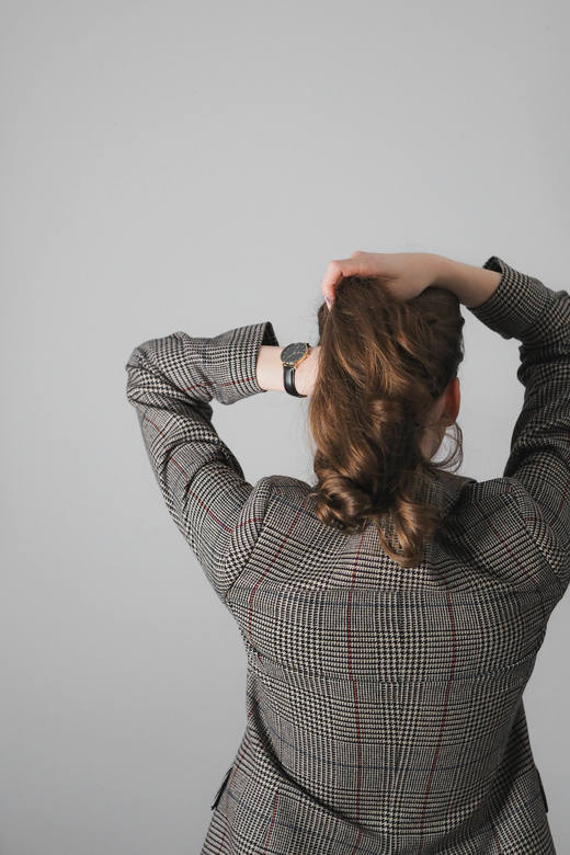 Espalda de un blazer de cuadros, con las manos en el cabello