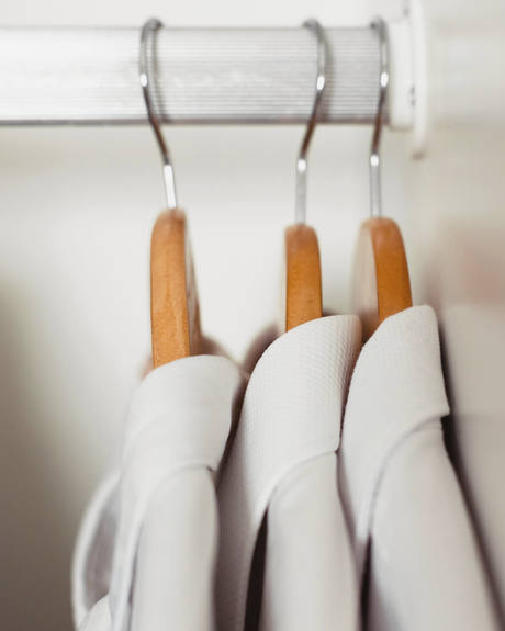 Camisas blancas colgadas en perchas de madera sobre una barra