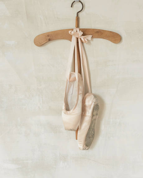 Zapatillas de baile color rosa pálido colgadas de una percha de madera