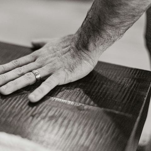 Mano apoyada sobre una tabla de madera, en blanco y negro
