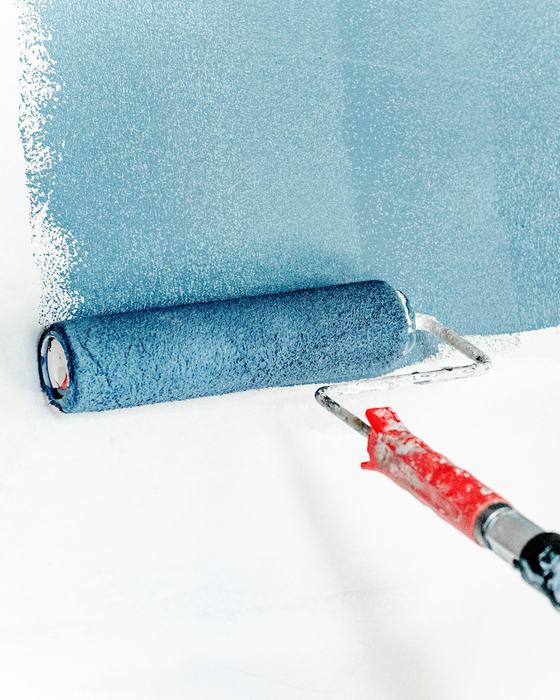 Un rodillo de pintura extendiendo pintura celeste