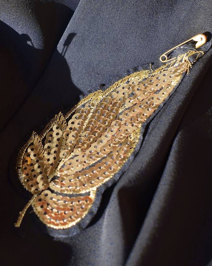 Hoja de lentejuelas doradas cosida a mano sobre una chaqueta gris